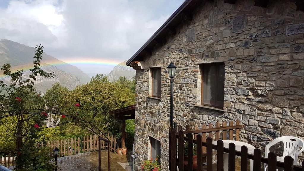 una casa de piedra con un arco iris en el fondo en QUERCIA ANTICA, en Masseria di Rusciano