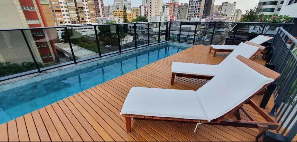 a balcony with white chairs and a swimming pool at Vesta - melhor localização Torres in Torres