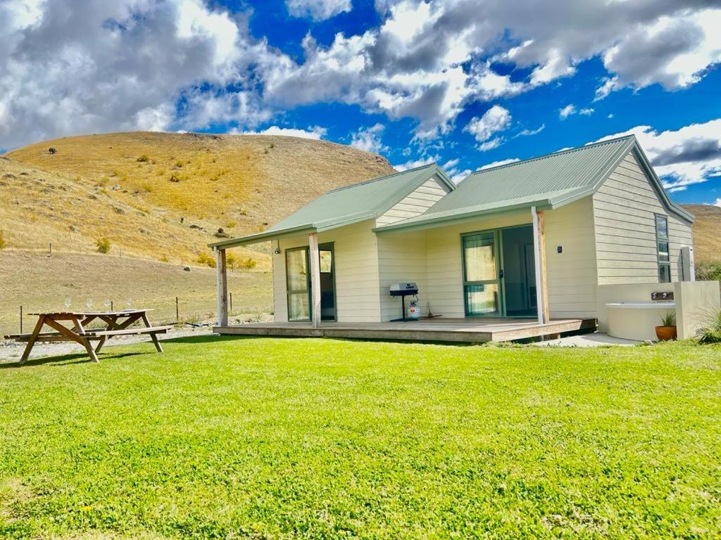 a house with a picnic table in front of a hill at Gold Miners Cottage in Tarras
