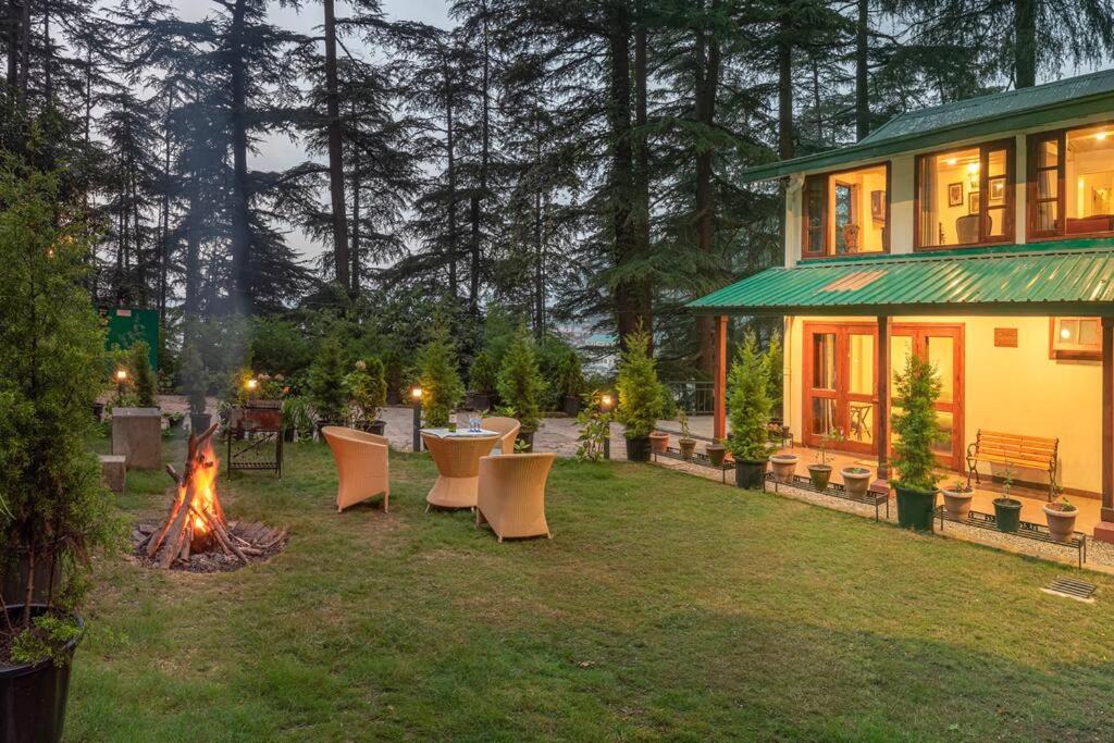 podwórko z kominkiem i domem w obiekcie Jais Cottage A Charming Hideaway w mieście Shimla