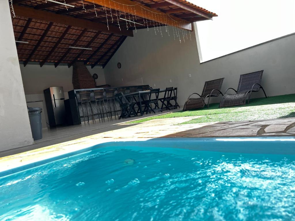 una piscina con sillas y una mesa en una casa en Chacara em Socorro- SP próx ao centro, com piscina e area gourmet, en Socorro