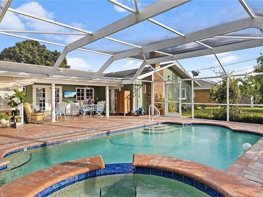 an outdoor swimming pool with a pergola and a house at 7 Palms Pool House in Cape Coral