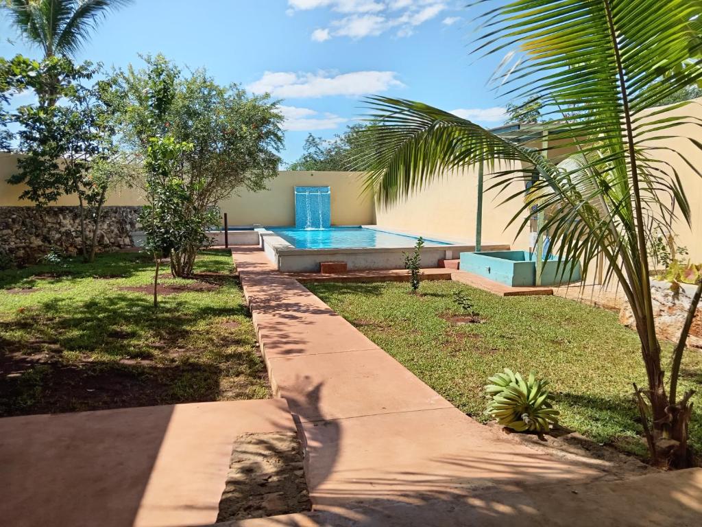 a backyard with a swimming pool and a palm tree at Casa Alegre Yucatan in Kanasín