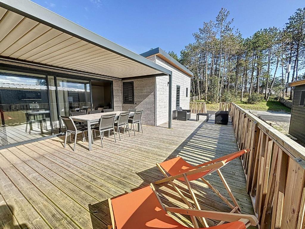 une terrasse en bois avec des chaises et une table. dans l'établissement Chalet de Standing 6 Pers. à Jullouville - Piscine Chauffée, Plage à Proximité, Wi-Fi Inclus - FR-1-361-536, à Jullouville