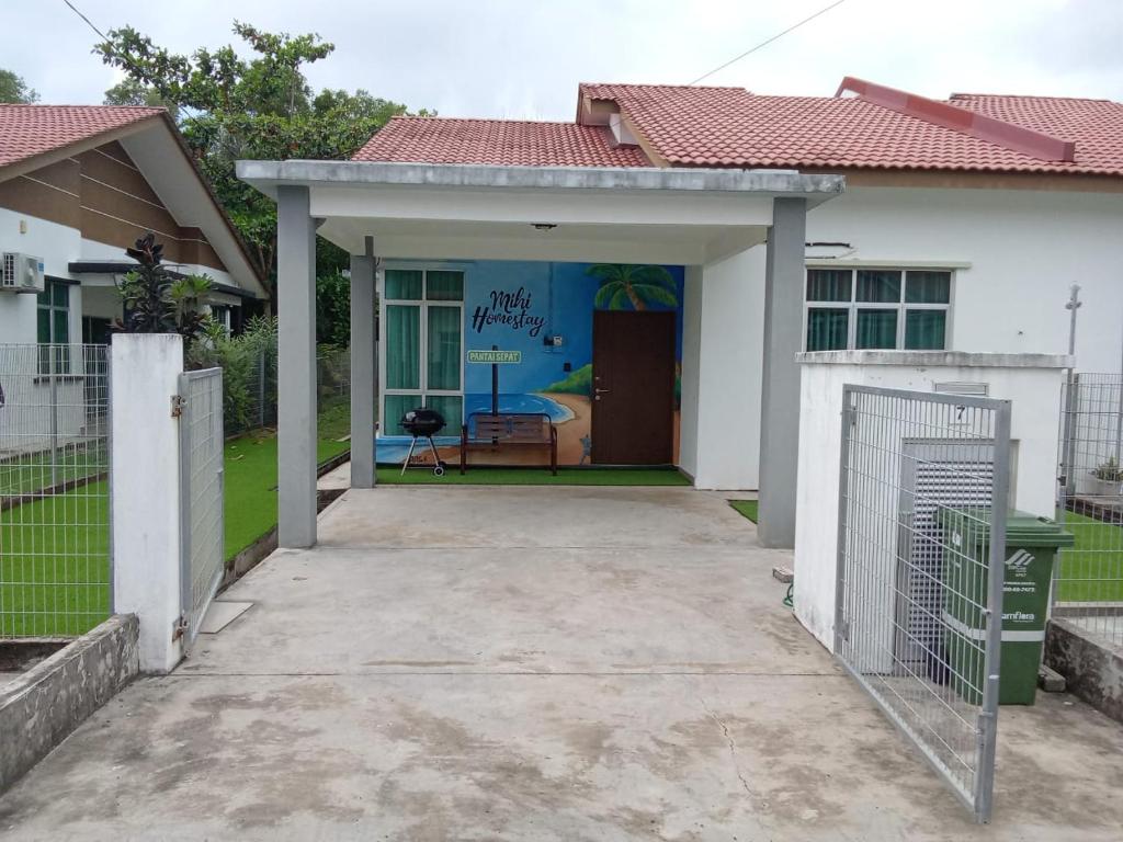 une maison blanche avec un garage et une allée dans l'établissement MIHI Homestay Pantai Sepat, à Kuantan