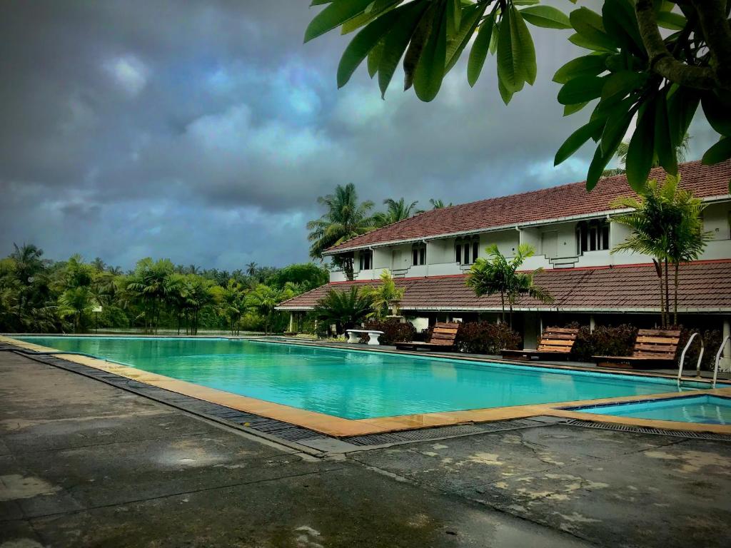 a swimming pool in front of a house at Green Island Nature lodge and Villa in Kammala South