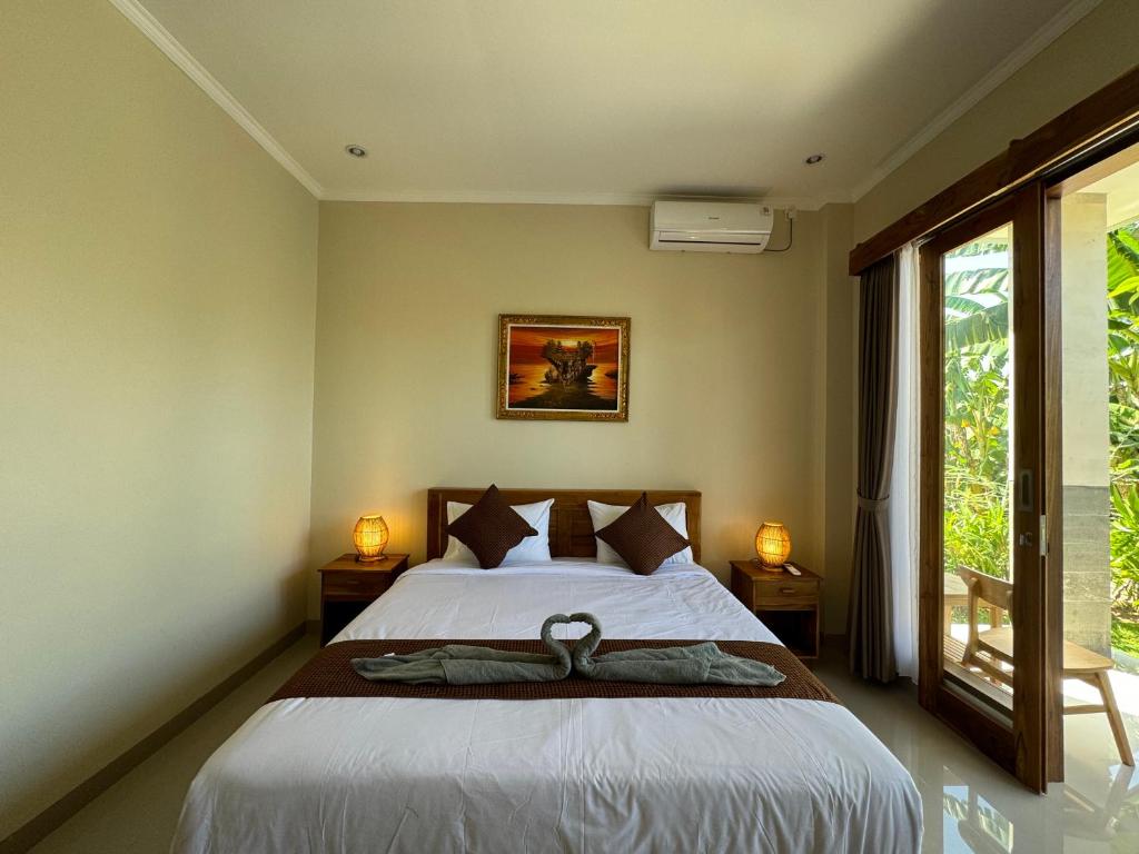 a bedroom with a bed and a large window at Canggu Nadi 2 Guest House in Canggu