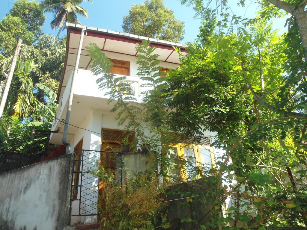 a white house with trees in front of it at SUPER SUN HOMESTAY in Katugastota