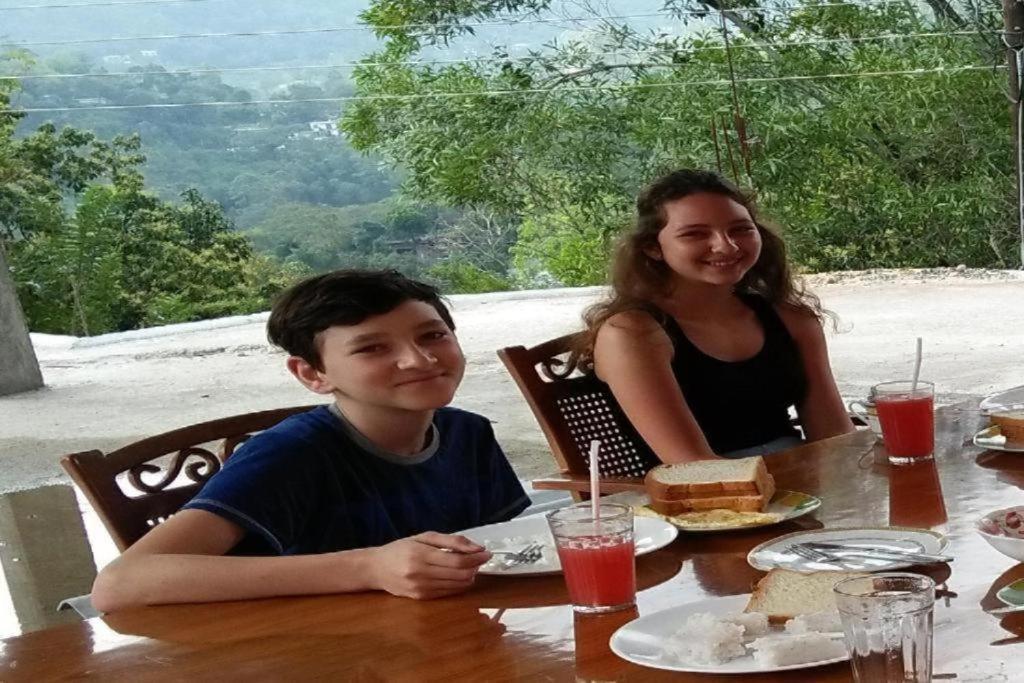 a boy and a woman sitting at a table with food at Mountain Top Guest in Bandarawela