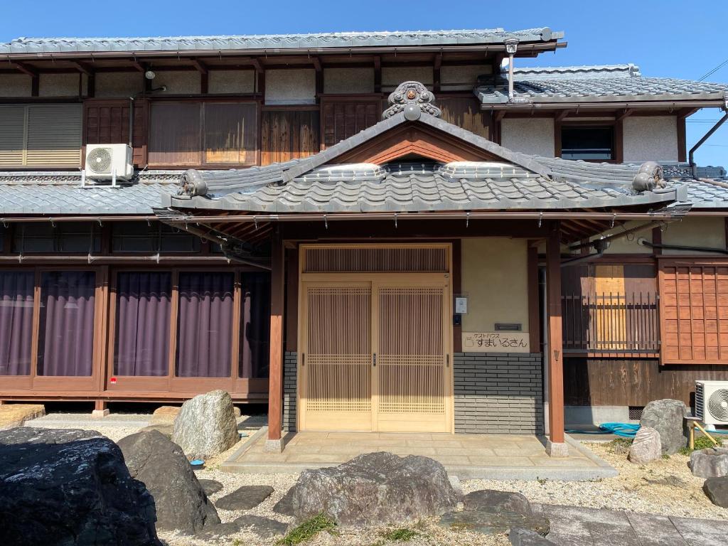 an asian house with a door and some rocks at ゲストハウスすまいるさん in Iba