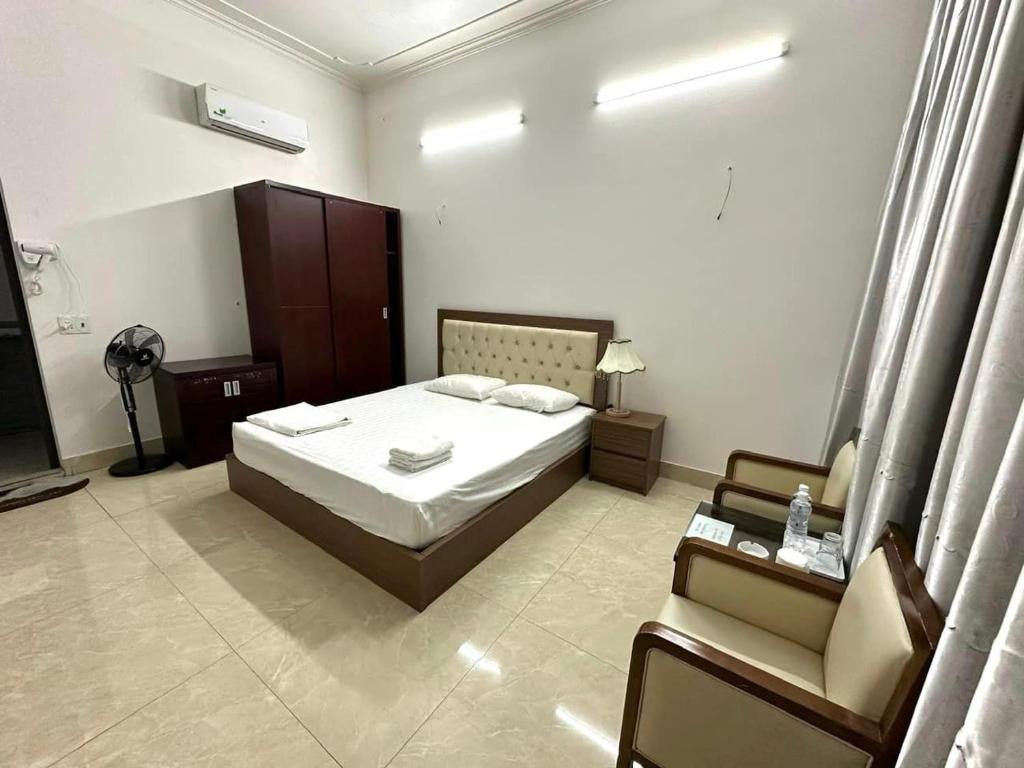 1 dormitorio con 1 cama y 1 silla en TRÀ MY HOTEL, en Ðức Long