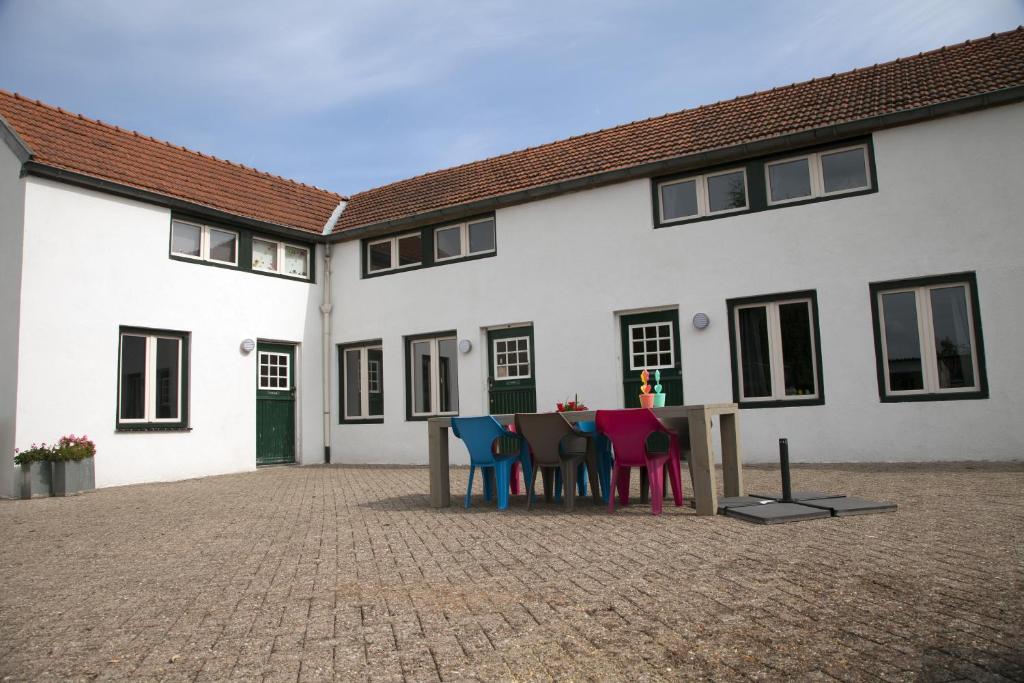 a table with colorful chairs in front of a building at Apartment Top van Epen in Epen