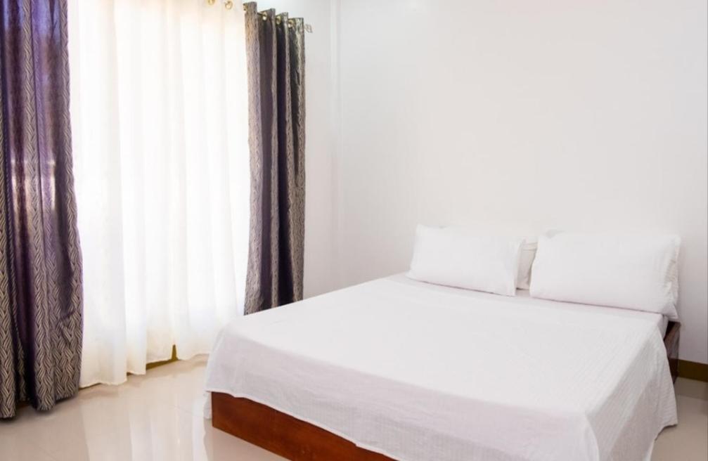 1 dormitorio con cama blanca y ventana en E and C tourist inn, en Dumaguete