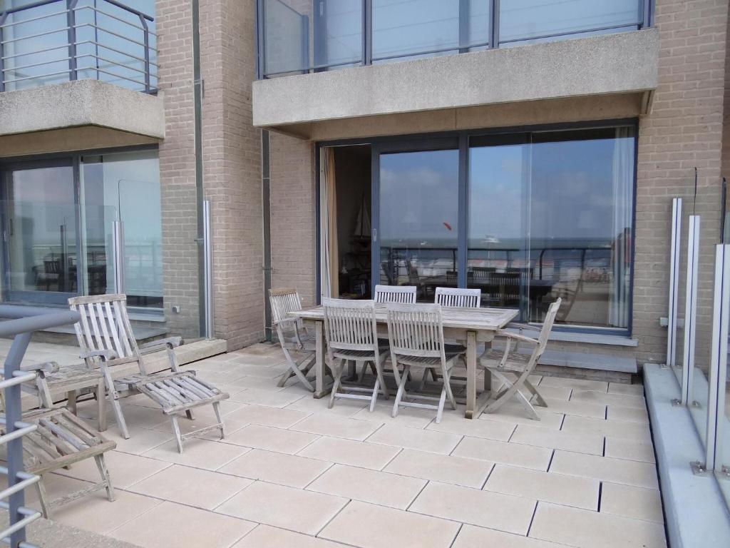 une terrasse avec une table et des chaises devant un bâtiment dans l'établissement Casino ABA0104 with beautiful sea views, à Nieuport
