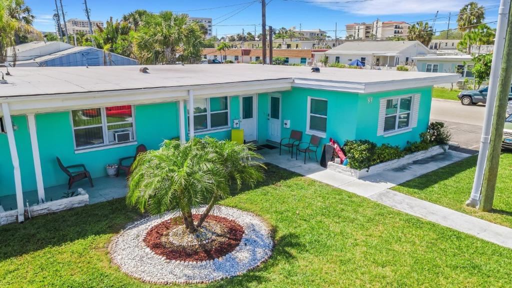 uma casa azul com uma palmeira em frente em Captain's Quarters - Weekly Rental apts em Clearwater Beach