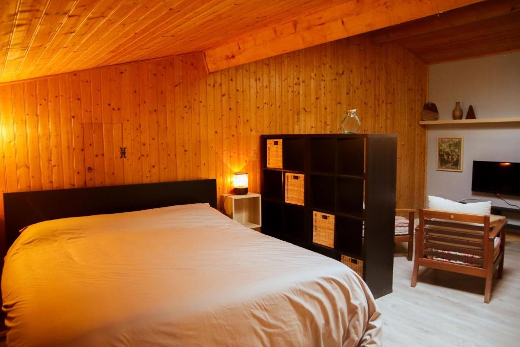 une chambre avec un lit et un mur en bois dans l'établissement Ferme de La Plante, à Saint-Aubin-de-Branne