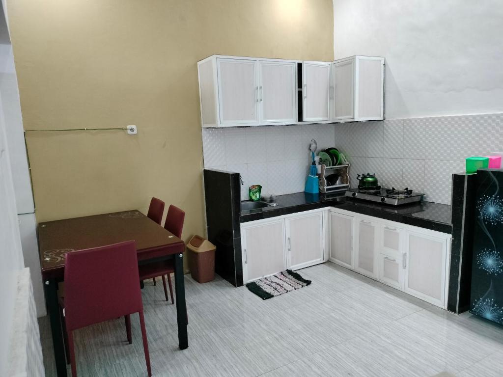 a kitchen with white cabinets and a table and a table and chairs at Vila Bumi Madinah Dau-Malang in Dau