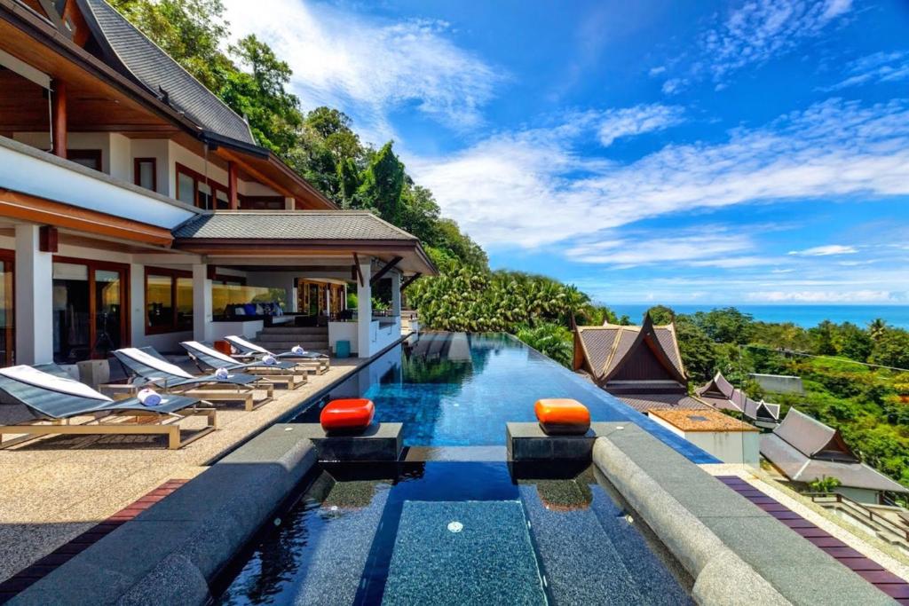 an infinity pool with lounge chairs next to a house at Seaview Villa at Surin Beach in Thalang