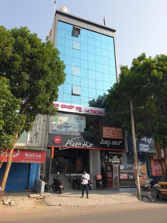 un hombre está parado frente a un edificio en Hotel SnV Inn, en Bangalore