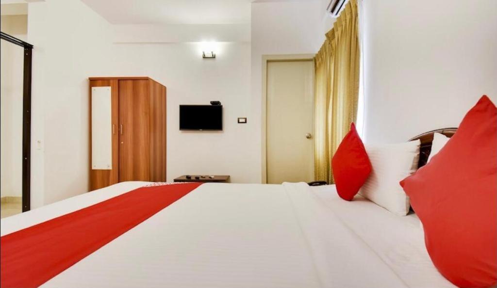 a bedroom with a large white bed with red pillows at PRIME SUITES in Bangalore