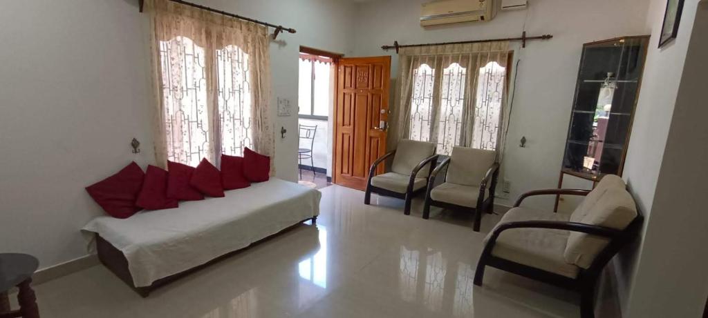 a living room with a couch and chairs and windows at Suburbs Holiday Home in Dabolim