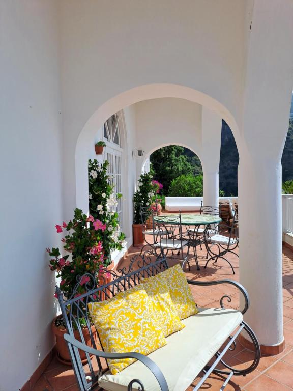 une terrasse avec un banc, une table et des chaises dans l'établissement Villa Poesia, à Praiano