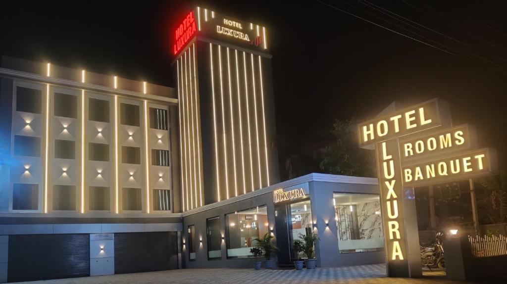 a hotel with a neon sign in front of a building at Hotel Luxura, Ahmedabad in Ahmedabad