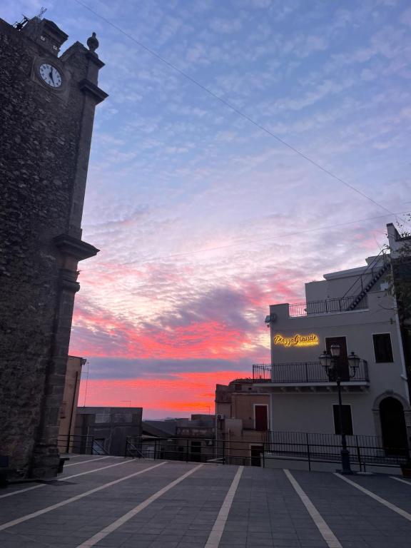 Un edificio con una torre de reloj con una puesta de sol al fondo. en Piazza Grande - Soggiorni Brevi, en San Cono