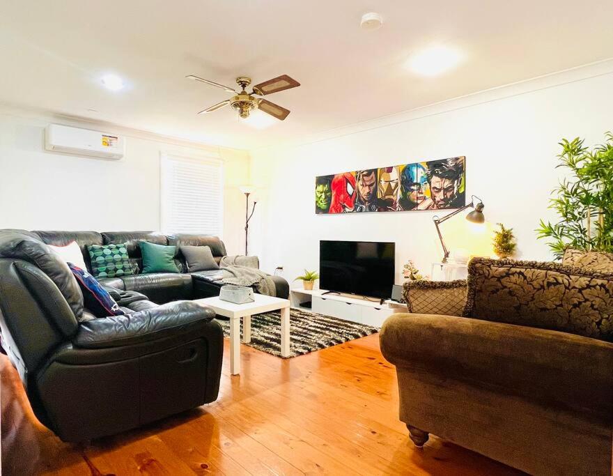 a living room with a couch and a tv at Penrith Relaxing Beauty 3BR Entire House Sleep 8 in Penrith