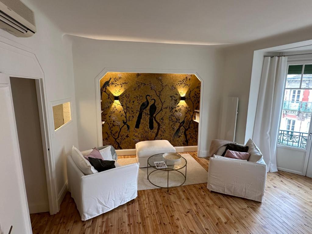 een woonkamer met 2 stoelen en een schilderij aan de muur bij Appartement Eugénie in Vichy