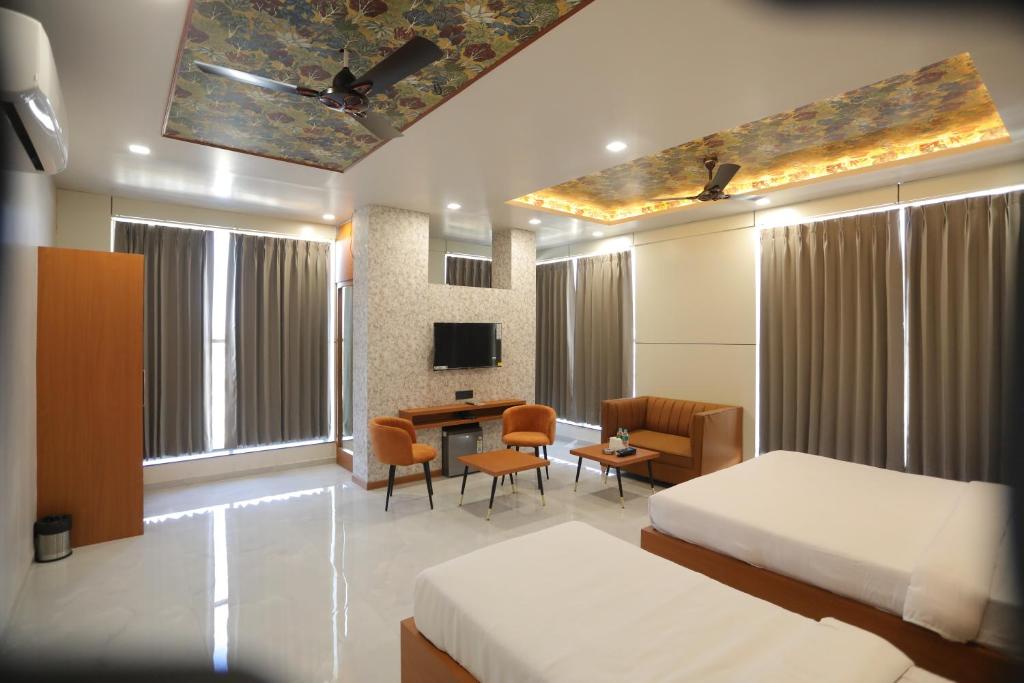 奇陶尔加尔Hotel Pride Of Chittor的一间有两张床、一张桌子和一台电视的酒店房间