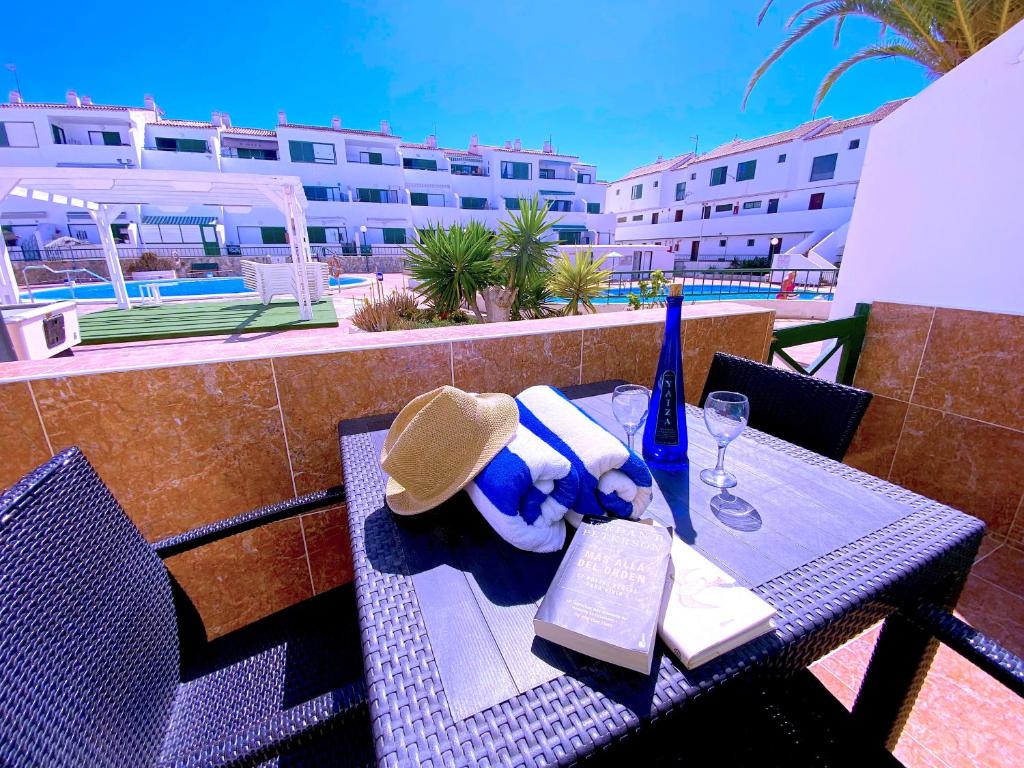 a table with a hat and a book on a balcony at Tropicalidays Sunset Palm in Costa Del Silencio