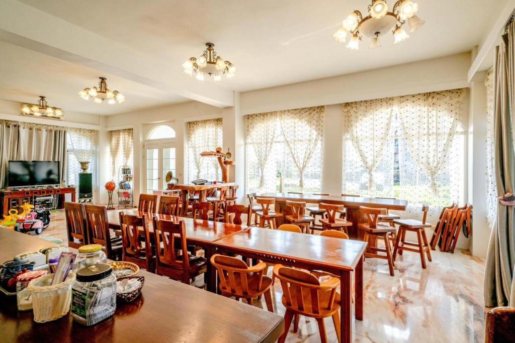 a dining room with tables and chairs and windows at Alps Garden B&amp;B in Wujie
