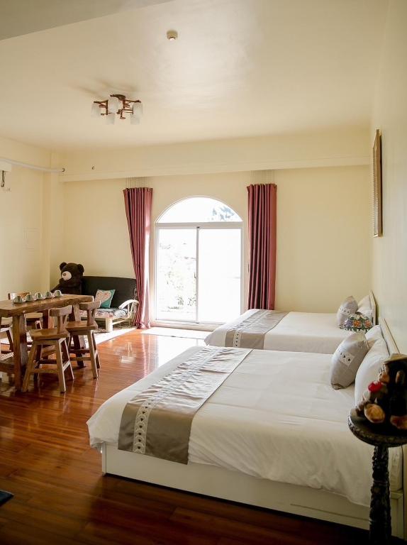 a bedroom with two beds and a table and a window at Alps Garden B&amp;B in Wujie