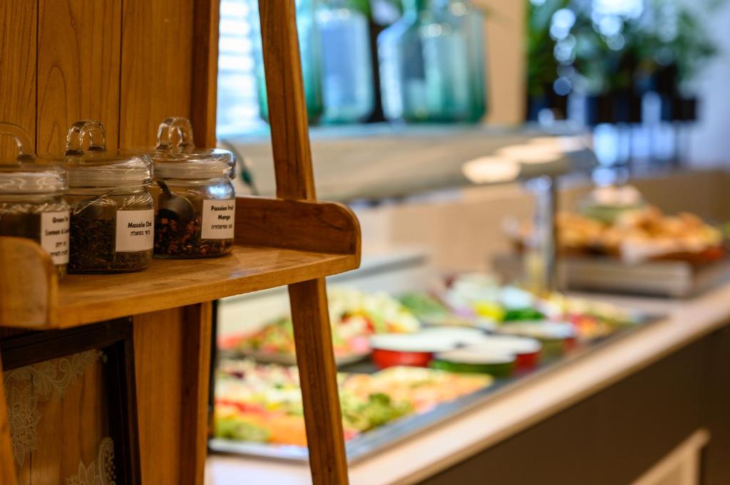 a buffet line with jars of food on a counter at Sadot Hotel Ben Gurion Airport - an Atlas Boutique Hotel in Assaf Harofeh