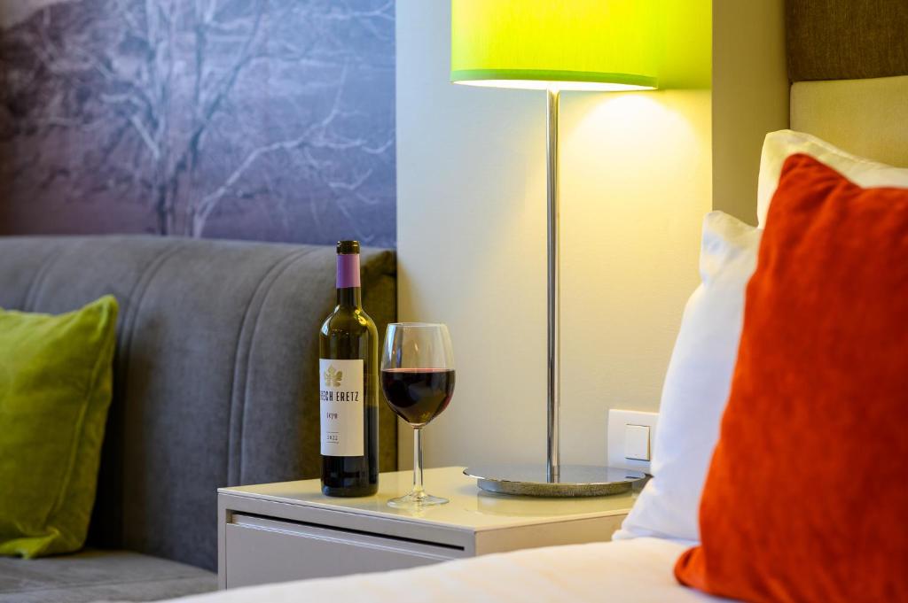 a bottle of wine and a glass on a table at Sadot Hotel Ben Gurion Airport - an Atlas Boutique Hotel in Assaf Harofeh