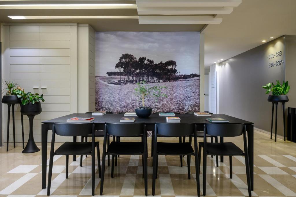 a dining room with a black table and chairs at Sadot Hotel Ben Gurion Airport - an Atlas Boutique Hotel in Assaf Harofeh