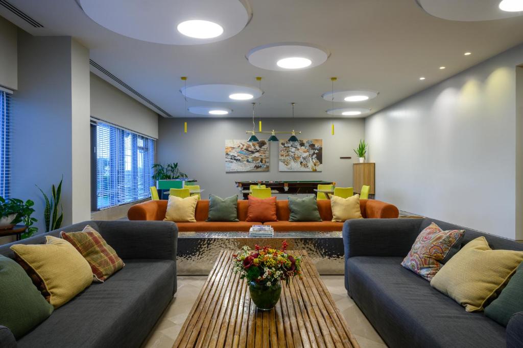 a living room with couches and a table at Sadot Hotel Ben Gurion Airport - an Atlas Boutique Hotel in Assaf Harofeh