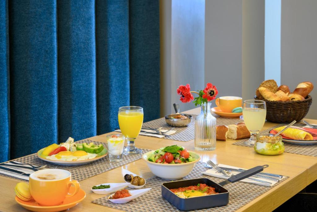 a table with breakfast foods and drinks on it at Sadot Hotel Ben Gurion Airport - an Atlas Boutique Hotel in Assaf Harofeh
