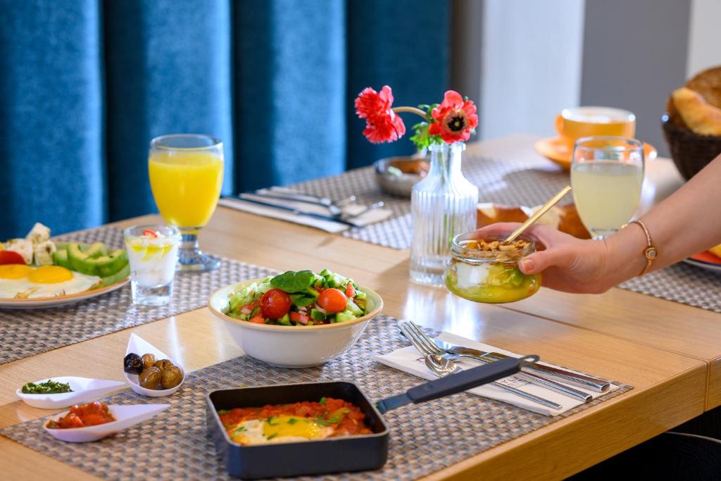 a table with breakfast foods and drinks on it at Sadot Hotel Ben Gurion Airport - an Atlas Boutique Hotel in Assaf Harofeh