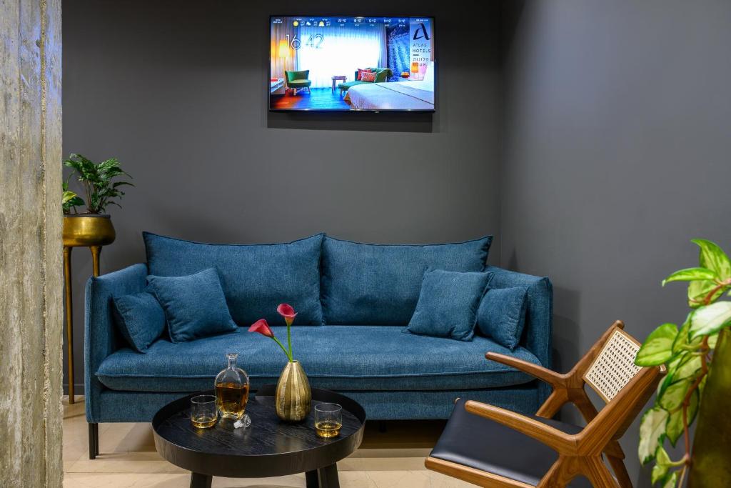 a living room with a blue couch and a tv at Sadot Hotel Ben Gurion Airport - an Atlas Boutique Hotel in Assaf Harofeh
