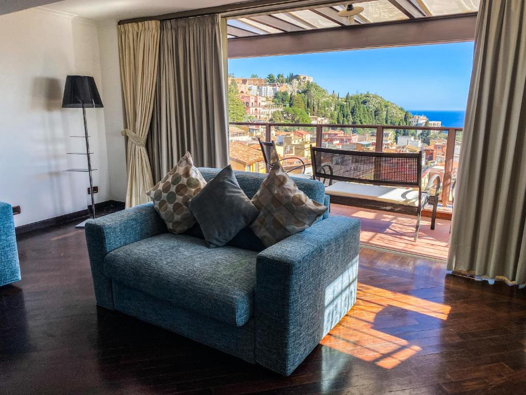 a living room with a blue couch and a balcony at Taormina Palazzo di Ferro in Taormina