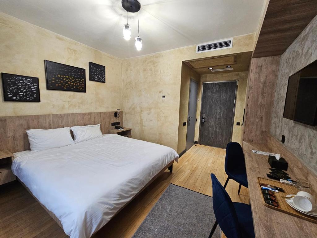 a bedroom with a large white bed and a tv at Aratta Royal Hotel in Gyumri
