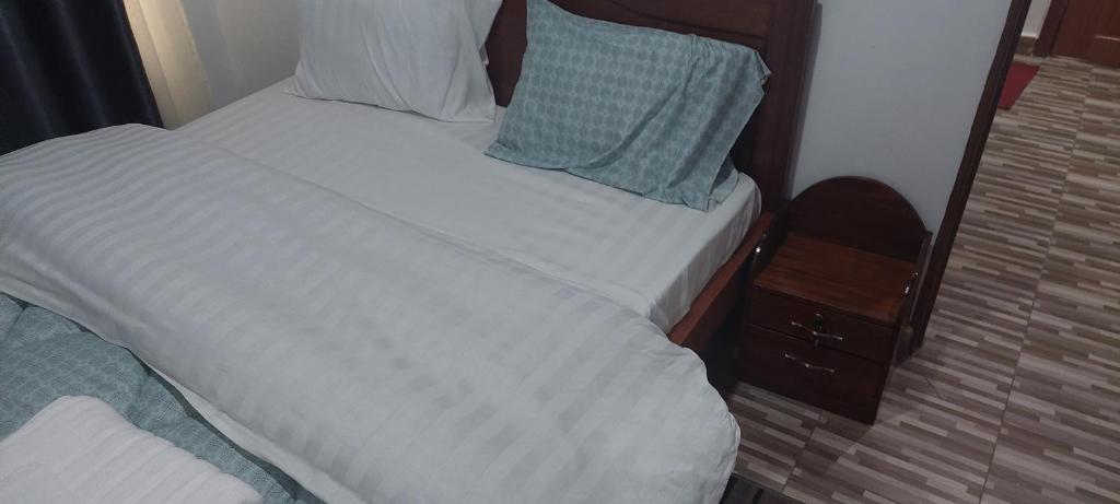 een bed met witte lakens en blauwe kussens erop bij RUbuto ABNB in Kigali