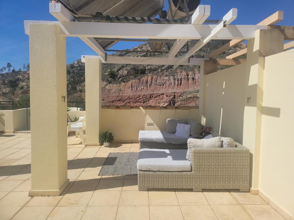 un patio con un sofá de mimbre y una pérgola en Ático con vistas al mar en Cala del Moral