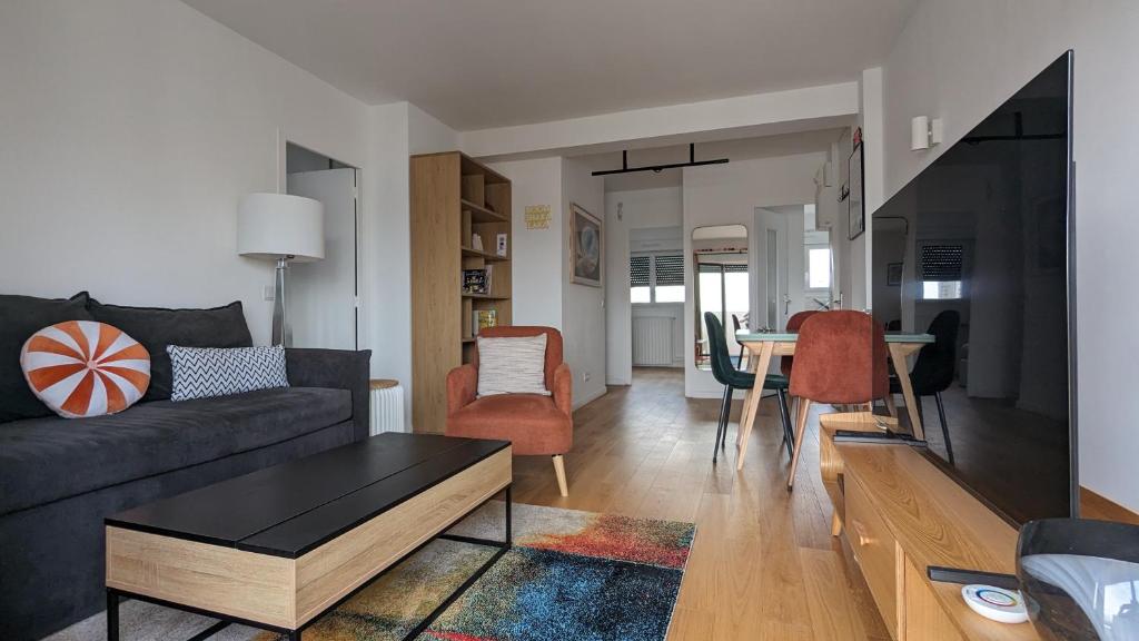 ein Wohnzimmer mit einem Sofa und einem Tisch in der Unterkunft Appartement lumineux et cosy avec balcon - 3P in Les Lilas