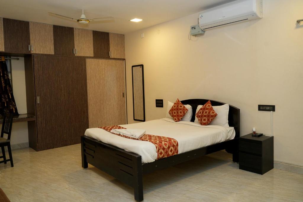 ein Schlafzimmer mit einem Bett mit orangefarbenen Kissen darauf in der Unterkunft Alexa Service Appartments (1BHK,2BHK with Kitchen) in Tirupati
