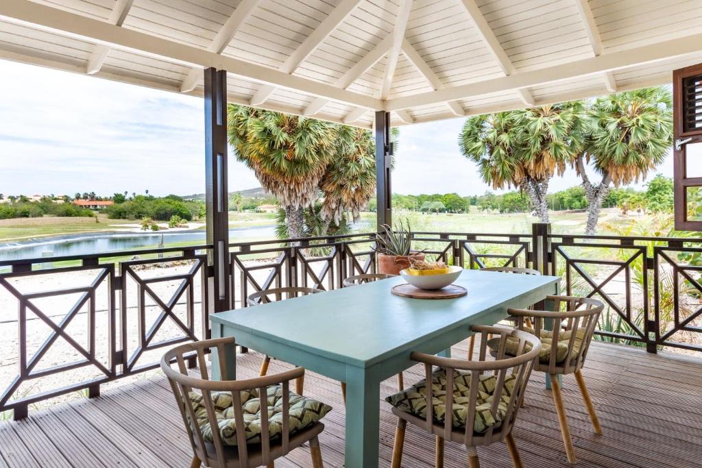 a table and chairs on a deck with palm trees at Villa at Blue Bay Resort with stunning view in Willemstad