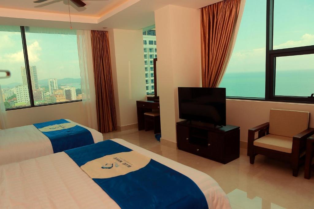 a hotel room with two beds and a flat screen tv at Blue Wave Hotel in Cửa Lô