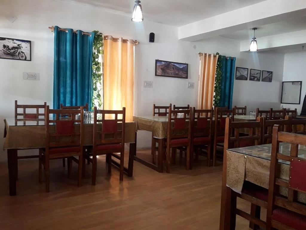 ein Esszimmer mit Tischen, Stühlen und blauen Vorhängen in der Unterkunft Khardung Laa View Hotel in Leh